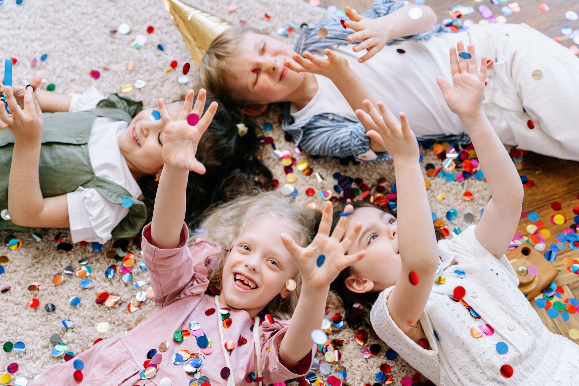 Joyful children having fun with colorful confetti indoors, enjoying a festive celebration.